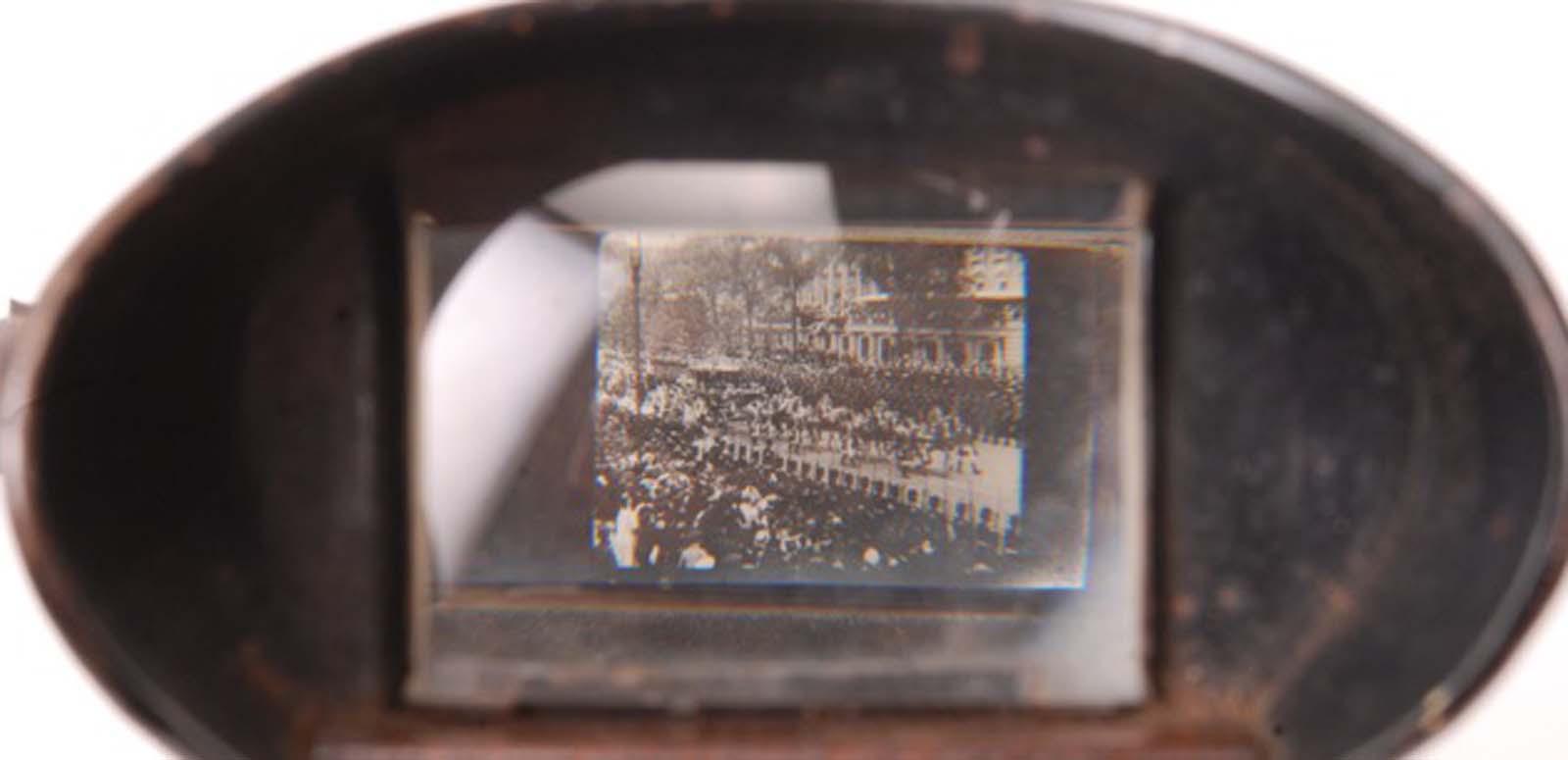 Looking through the viewing lens of a kinora at an image of a crowd scene.