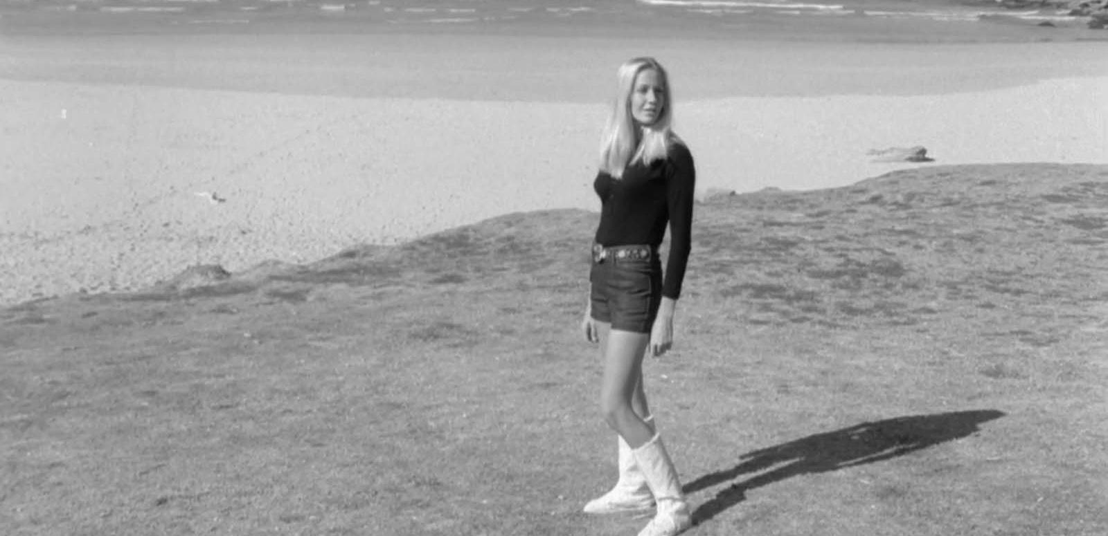 A young woman models a pair of knee-length ugg boots at the beach in 1971