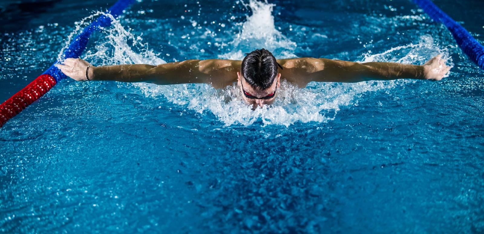 A man swimming a butterfly stroke in an Olympic pool