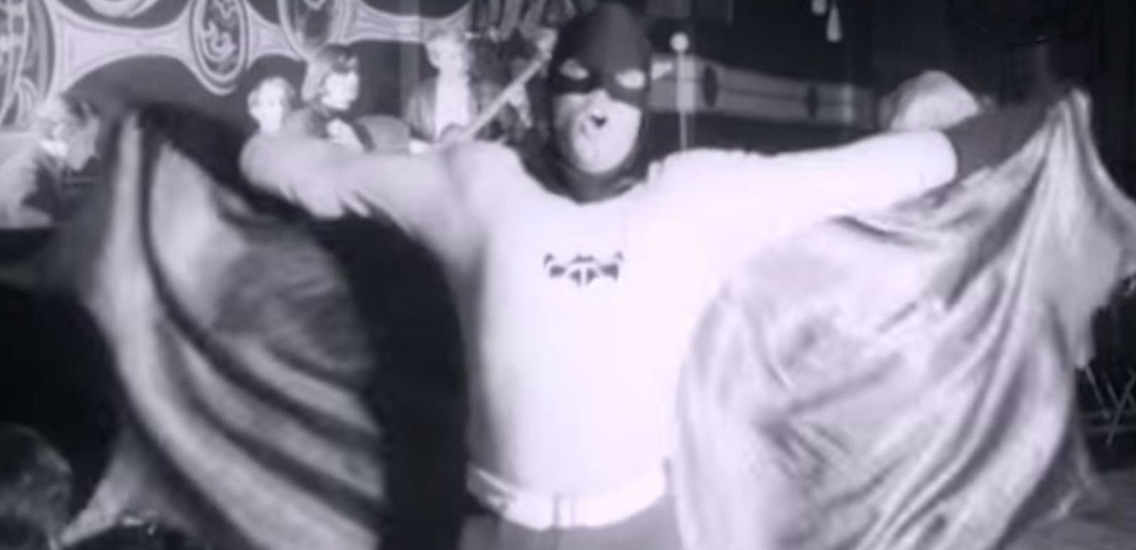 Man dressed up as batman dancing at a nightclub with go-go dancers.