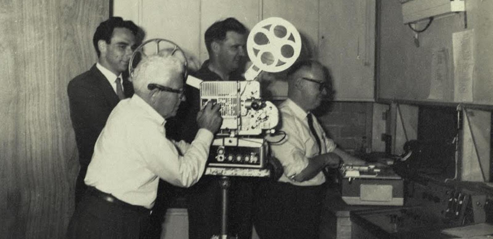 Four men operating a film projector