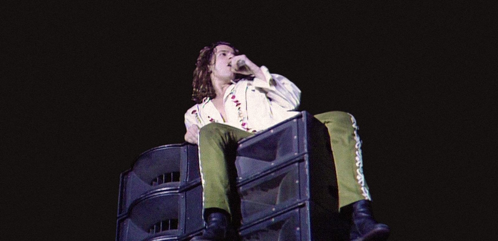 Michael Hutchence of INXS in concert, singing while seated on a loudspeaker