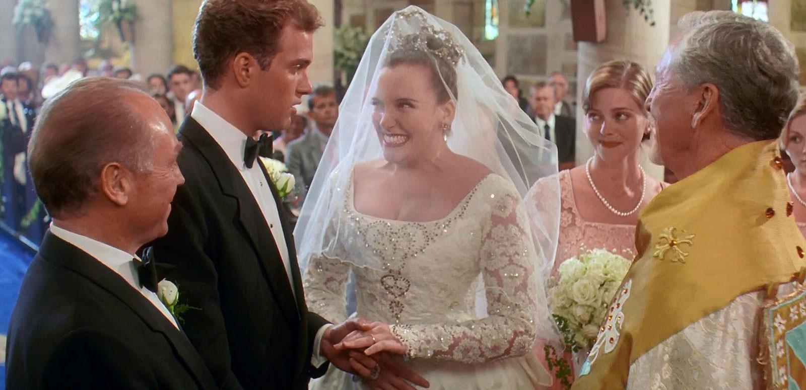 A scene from Muriel's Wedding where the main character, Muriel (Toni Collette) is getting married. She's standing at the alter with her groom, his best man, her bridesmaid and a minister.