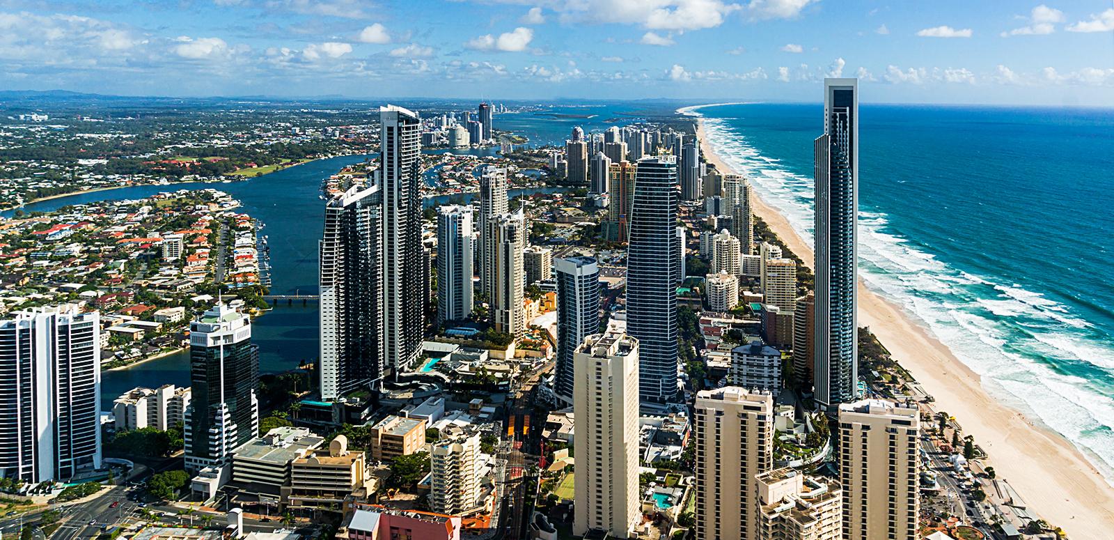 Aerial photo of the Gold Coast showing long stretch of beach, ocean and high rise buildings.