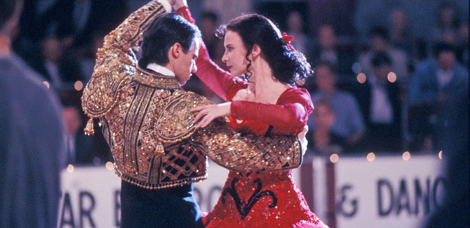 Paul Mercurio and Tara Morice in a scene from the film Strictly Ballroom. The are pictured from the waist up in a dancing pose and wearing Spanish-style costumes.