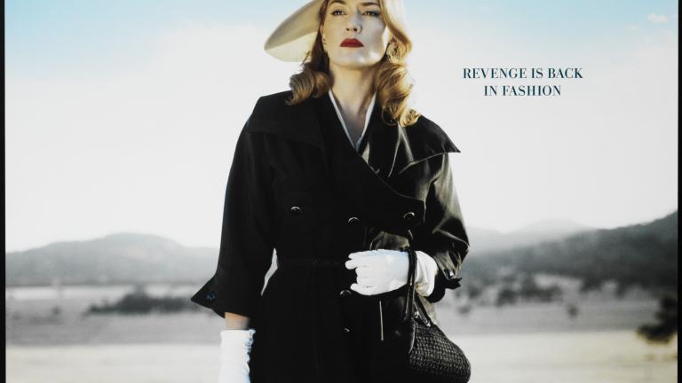 Movie poster for 'The Dressmaker' featuring Kate Winslet holding a Singer sewing machine standing in a paddock with blue sky in the background. Title is in dark blue along top and credits are in white text at bottom.