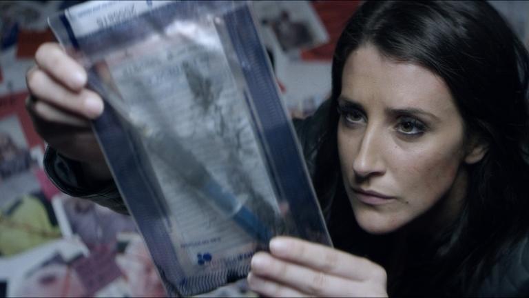 A woman examines a document in a plastic sachel.