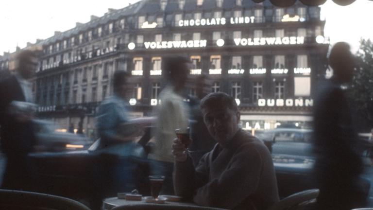 Graham Kennedy seated at an outside cafe in Paris enjoying a drink