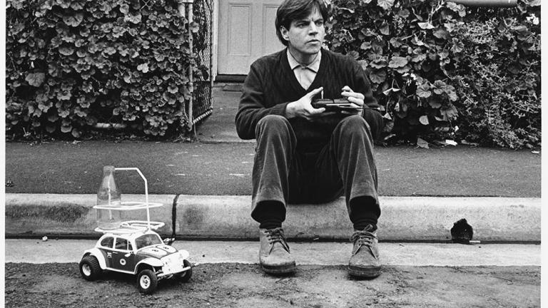 Malcolm sits on the curb sending his remote controlled car to the corner shop for milk