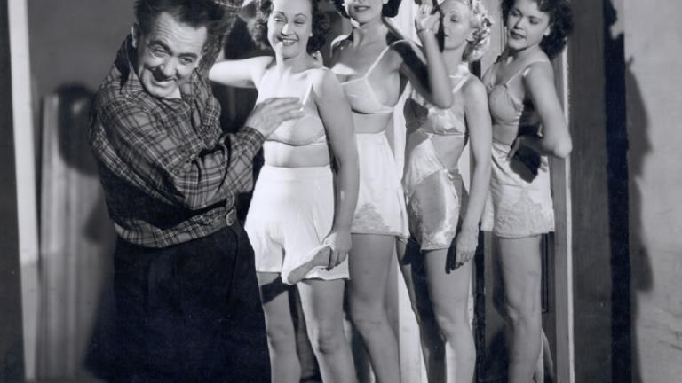 Four woman in underwear act as if to strike a cowering man.
