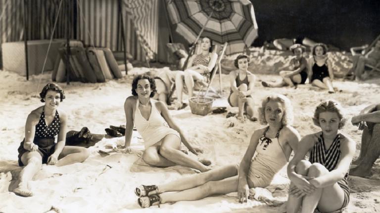 A group of people lounging on a film set made to look like a beach.
