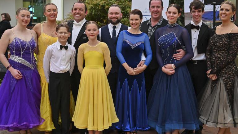 A troupe of ballroom dancers pose for a group photo in the NFSA courtyard