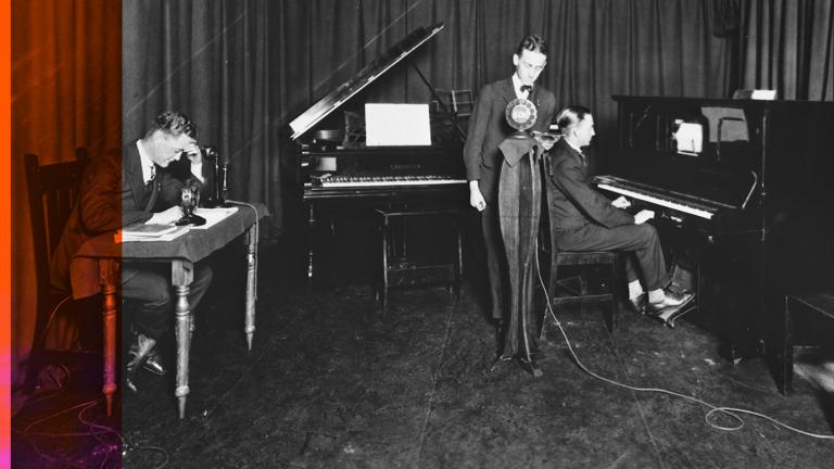 Recording a radio program from a home recording studio in 1927. One man sits at a desk, another at a piano while a third stands behind a microphone.