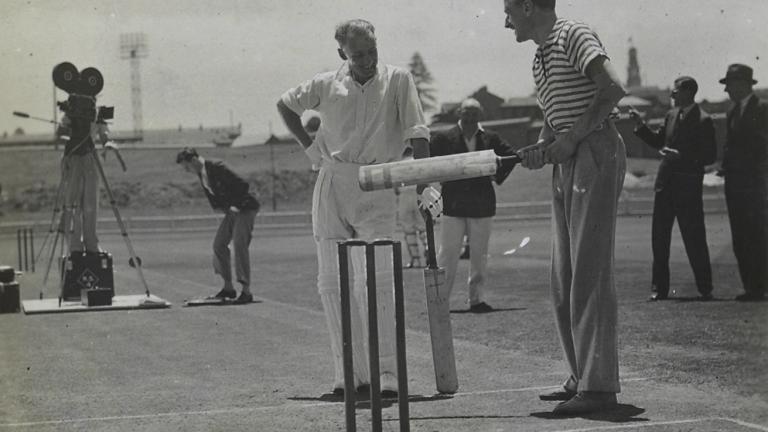 Donald Bradman and director Miles Mander in discussion on a cricket pitch