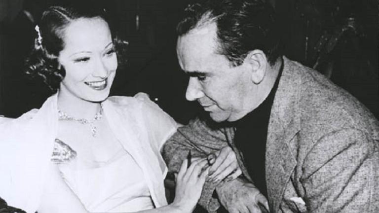 Merle Oberon linking arms with William K Howard.