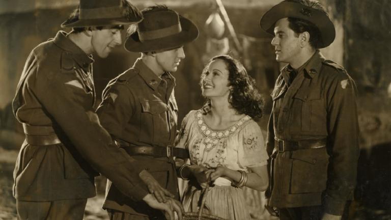 Betty Bryant on the set of Forty Thousand Horsemen holding a basket of oranges with Chips Rafferty and other actors dressed in uniform.