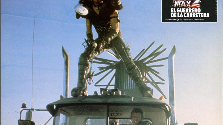 Mad Max 2 lobby card showing Wez (Vernon Wells) riding on top of a truck cabin
