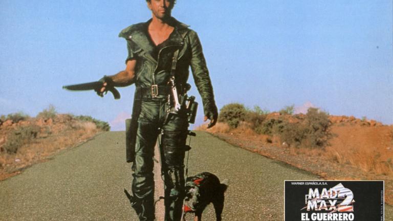 Mad Max 2 lobby card featuring Max (Mel Gibson) with his dog walking down a road holding a sawn-off shotgun.