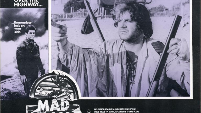Lobby card for Max Max shows Toecutter (Hugh Keays-Byrne) pointing and holding a rifle.