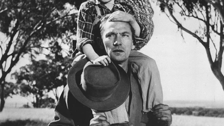 Peter Finch with Dana Wilson on his shoulders holding his hat on a country road