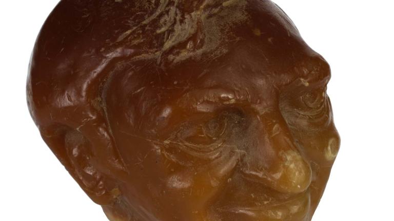 Sculpted orange wax candle of Graham Kennedy's head.