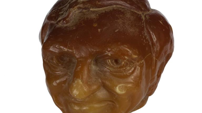 Sculpted orange wax candle of Graham Kennedy's head.