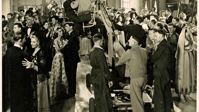 A ballroom full of people dancing with a film crew in the centre of the room.