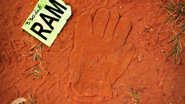 A glove submerged in red dust next to a piece of paper with RAM on it