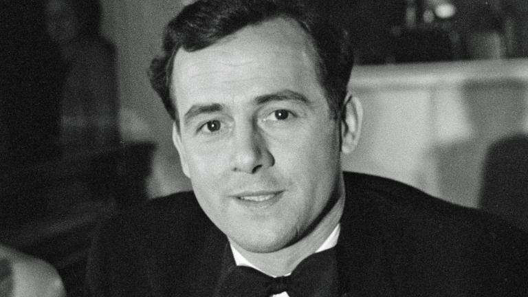 Head and shoulders shot of a man in a suit and bow tie looking at camera.