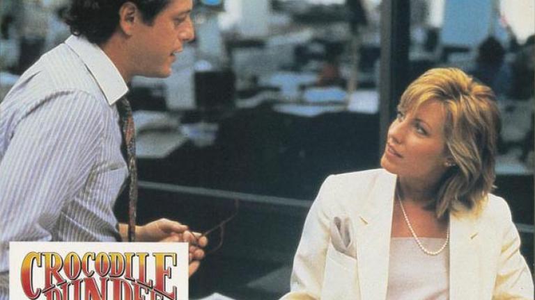 Lobby card depicting Sue Charlton (Linda Kozlowski) speaking with her newspaper editor beau Richard Mason (Mark Blum)