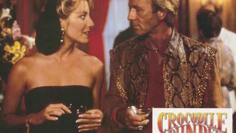 Lobby card depicting Linda Kozlowski as Sue Charlton and Paul Hogan as Mick Dundee looking into each other's eyes
