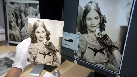 Conservator holds paper photograph up against digital copy of same photograph