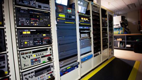 A rack metal rack houses video tape players and monitors