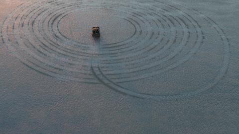 A four-wheel drive that has made a large spiraling tyre track in the sand