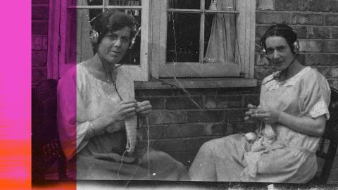 Two women sitting outside knitting and listening to the radio through headphones, c1920s