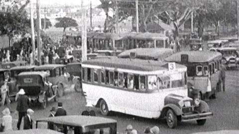 A picture from 1928 of ordered traffic chaos. Buses, trams and automobiles all crowd Anzac Parade Junction with fig trees in the background.