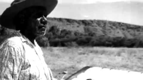 Indigenous artist Albert Namatjira standing in the outback, pictured in profile and looking out at the landscape