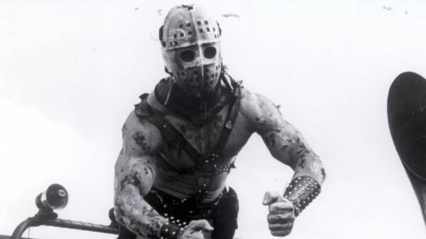 Mad Max 2 villain Humungus strikes a muscular pose with his face covered by a hockey mask