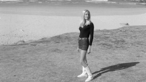A young woman models a pair of knee-length ugg boots at the beach in 1971