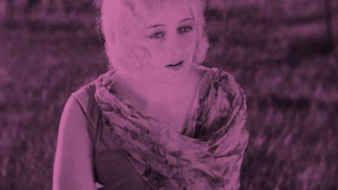 A rose-pink tinted image of a woman looking off into the distance.