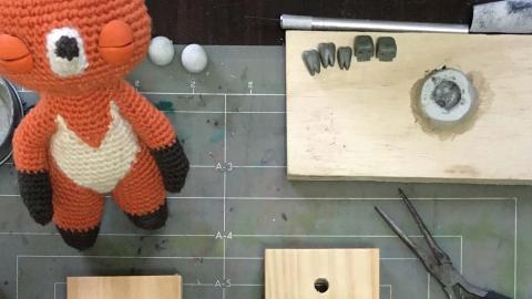 A crocheted animal created for an animated film sits on a workbench awaiting completion 