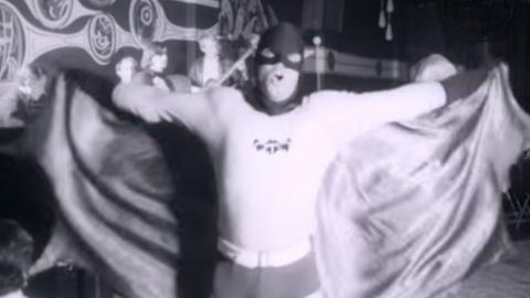 Man dressed up as batman dancing at a nightclub with go-go dancers.