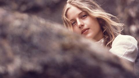 Anne Louise Lambert as Miranda, peering over a rock and looking into the distance in a scene from Picnic at Hanging Rock.