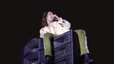 Michael Hutchence of INXS in concert, singing while seated on a loudspeaker