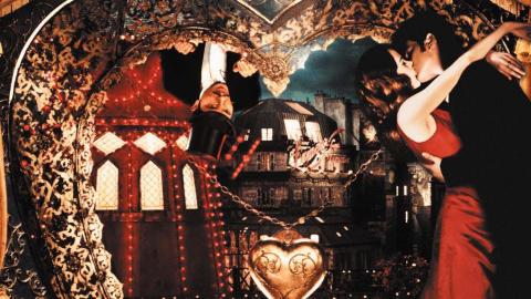 Satine and Christian embrace in her chambers while Toulouse-Lautrec peers down at them from outside a heart-shaped window, in a scene from Moulin Rouge!