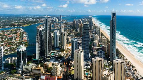Aerial photo of the Gold Coast showing long stretch of beach, ocean and high rise buildings.