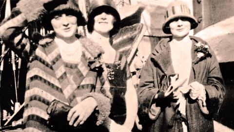 The McDonagh sisters, Isabel, Paulette and Phyllis, pictured from the waist up, wearing coats and hats and standing on the deck of a ship.