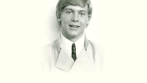 Head and shoulders publicity image of a young John Farnham, circa early 1970s, he's wearing a suit and tie looking directly at the camera.