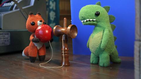 Animation still of a knitted dinosaur and a knitted fox