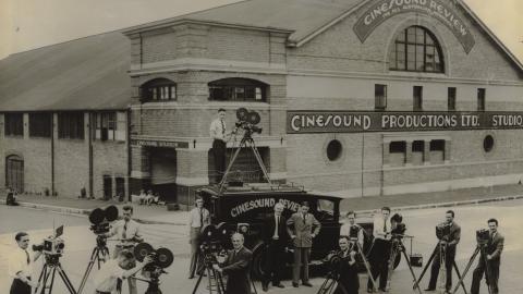 Several cameramen pose outside the Cinesound productions studio with their cameras